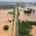 
              FILE - Workers gather along a section of flooded railway in Shangrao in central China's Jiangxi province on June 21, 2022. From the snowcapped peaks of Tibet to the tropical island of Hainan, China is sweltering under the worst heatwave in decades while rainfall hit records in June. (Chinatopix via AP, File)
            