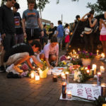 
              Dozens of mourners gather for a vigil near Central Avenue and St. Johns Avenue in downtown Highland Park, one day after a gunman killed at least seven people and wounded dozens more by firing an AR-15-style rifle from a rooftop onto a crowd attending Highland Park's Fourth of July parade, Tuesday, July 5, 2022 in Highland Park, Ill.. (Ashlee Rezin/Chicago Sun-Times via AP)
            