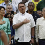 
              Brazil's President Jair Bolsonaro, center, who is running for a second term, center, listens to the national anthem flanked by his wife Michelle Bolsonaro, left, and running-mate General Braga Neto during a rally to launch his reelection bid, in Rio de Janeiro, Brazil, Sunday, July 24, 2022. Brazil's general elections are scheduled for Oct. 2, 2022. (AP Photo/Bruna Prado)
            