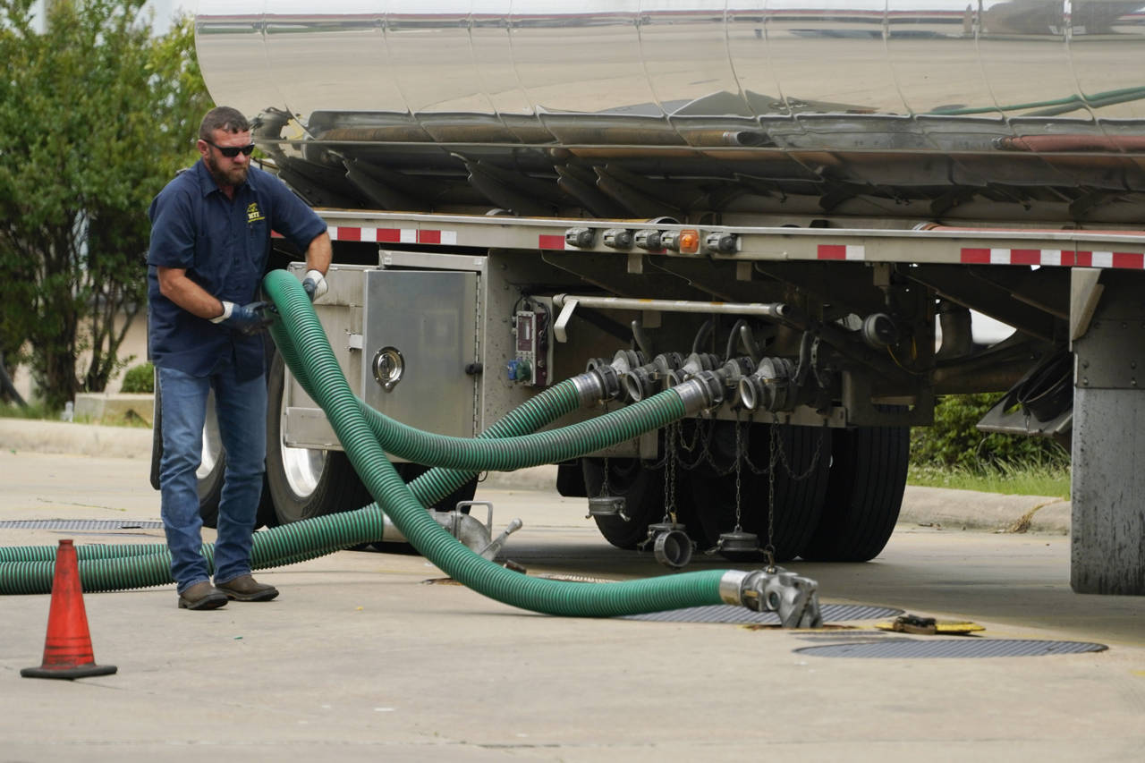 FILE - A gas tank driver adjusts his hose hookup to an underground tank on May 24, 2022, in Jackson...