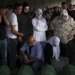 
              Muslim men and women pray next to the coffins of their relatives, victim of the 1995 Srebrenica genocide in Potocari, Bosnia, Friday, July 8, 2022. The remains of the 50 recently identified victims of Srebrenica massacre, Europe’s only acknowledged genocide since World War II, arrived at the Memorial centre in Potocari where they will be buried on July 11. (AP Photo/Armin Durgut)
            