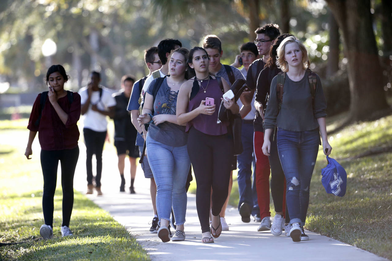 FILE - Groups of students leave Marjory Stoneman Douglas High School after a shooting, Wednesday, F...