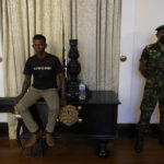 
              Sri Lanka army officer stands guard as a protester sits on the table inside the official residence of president Gotabaya Rajapaksa fourth days after it was stormed by anti government protesters in Colombo in Colombo, Sri Lanka, Wednesday, July 13, 2022. The president of Sri Lanka fled the country early Wednesday, days after protesters stormed his home and office and the official residence of his prime minister amid a monthslong economic crisis that triggered severe shortages of food and fuel.(AP Photo/Rafiq Maqbool)
            