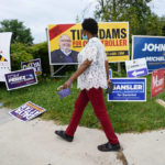 
              A woman walks in front of campaign signs during Maryland's primary election, Tuesday, July 19, 2022, in Baltimore. (AP Photo/Julio Cortez)
            