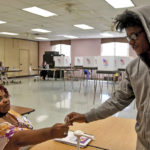 
              Election judge Deborah Claude-Jones, left, gives a sticker to Joel Evans, 21, right, after he voted at Randallstown Community Center in Baltimore , Tuesday, July 19, 2022. (Barbara Haddock Taylor/The Baltimore Sun via AP)
            
