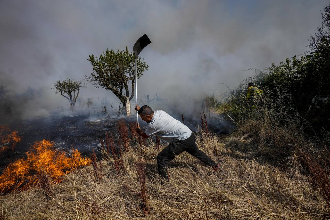 FILE - A local resident fights a forest fire with a shovel during a wildfire in Tabara, north-west ...
