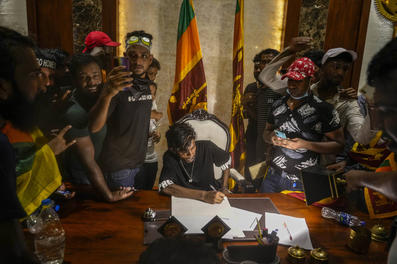 A protester sits on a chair surrounded by others after storming the Sri Lankan Prime Minister Ranil...