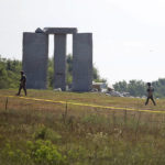 
              Law enforcement officials walk around the damaged Georgia Guidestones monument near Elberton, Ga., on Wednesday, July 6, 2022. The Georgia Bureau of Investigation said the monument, which some Christians regard as satanic, was damaged by an explosion before dawn. (Rose Scoggins/The Elberton Star via AP)
            
