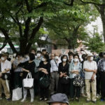 
              Bystanders gather at a park across from Zojoji temple before the funeral of former Japanese Prime Minister Shinzo Abe in Tokyo on Tuesday, July 12, 2022. Abe was assassinated Friday while campaigning in Nara, western Japan. (AP Photo/Hiro Komae)
            