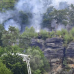 
              A firefighter uses a hose to fight wildfires in the Ceske Svycarsko, Czech Switzerland National Park, near Hrensko, Czech Republic, Wednesday, July 27, 2022.  (Ondrej Hajek/CTK via AP)
            