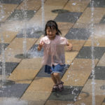 
              FILE - A girl runs through a fountain at an outdoor shopping area on an unseasonably hot day in Beijing, Saturday, June 25, 2022. From the snowcapped peaks of Tibet to the tropical island of Hainan, China is sweltering under the worst heatwave in decades while rainfall hit records in June. (AP Photo/Mark Schiefelbein, File)
            