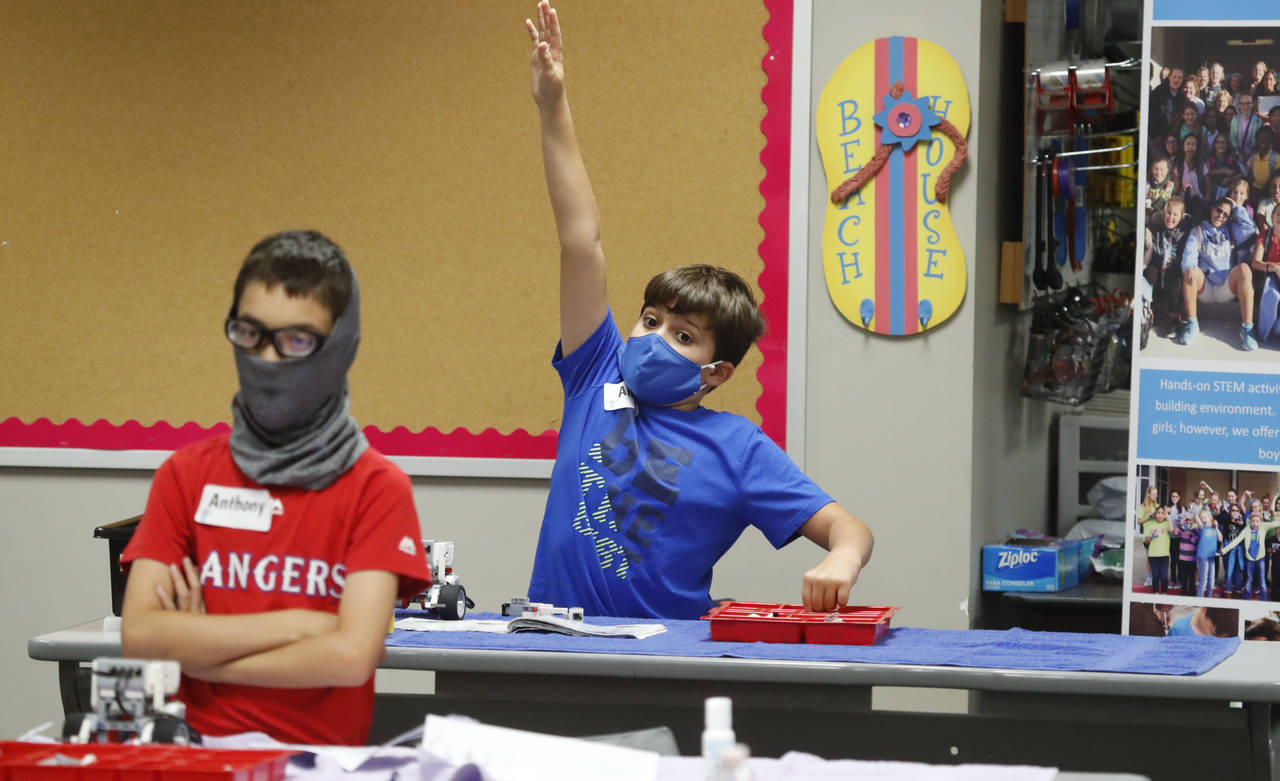 FILE - Aiden Trabucco, right, wears a mask as he raises his hand to answer a question behind Anthon...