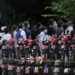 
              People wait in line along Buddhist guardian deities of travelers and children before their prayers to pay respect for former Japanese Prime Minister Shinzo Abe at Zojoji temple before his funeral in Tokyo on Tuesday, July 12, 2022. Abe was assassinated Friday while campaigning in Nara, western Japan. (AP Photo/Hiro Komae)
            