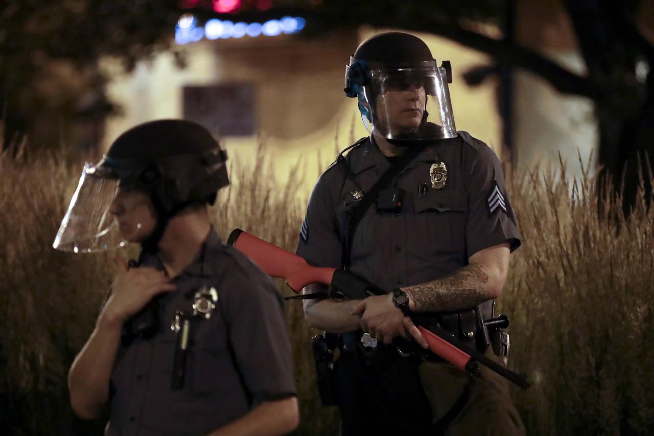 FILE - A Kansas City policeman holds a non-lethal weapon as he watches protesters late Wednesday, J...