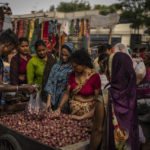 
              A roadside vendor packs onions in plastic bags as women shop at a weekly market in New Delhi, India, Wednesday, June 29, 2022. India banned some single-use or disposable plastic products Friday as a part of a longer federal plan to phase out the ubiquitous material in the nation of nearly 1.4 billion people. (AP Photo/Altaf Qadri)
            