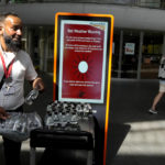 
              A railway worker hands out bottles of water to passengers at King's Cross railway station where there are train cancellations due to the heat in London, Tuesday, July 19, 2022. Millions of people in Britain woke from the country's warmest-ever night on Tuesday and braced for a day when temperatures could break records, as a heat wave scorching Europe walloped a country not built for such extremes. (AP Photo/Kirsty Wigglesworth)
            