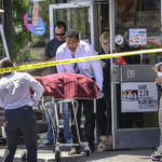 
              Authorities remove a body from a 7-Eleven after a clerk was fatally shot on Monday, July 11, 2022, during a robbery in Brea, Calif. (Mindy Schauer/The Orange County Register via AP)
            