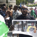 
              A man shows a picture of the victim Nigerian street vendor Alika Ogorchukwu, in Civitanova Marche, Italy, Saturday, July 30, 2022. (AP Photo/Chiara Gabrielli)
            