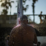 
              A man cools off in a public shower at a beach during a hot, sunny day in Barcelona, Spain, Thursday, July 21, 2022. (AP Photo/Francisco Seco)
            