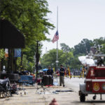 
              A flag hangs at half staff as members of the FBI's Evidence Response Team Unit investigate in downtown Highland Park, Ill., the day after a deadly mass shooting on Tuesday, July 5, 2022.   Police say the gunman who attacked an Independence Day parade in suburban Chicago fired more than 70 rounds with an AR-15-style gun.   (Ashlee Rezin /Chicago Sun-Times via AP)
            