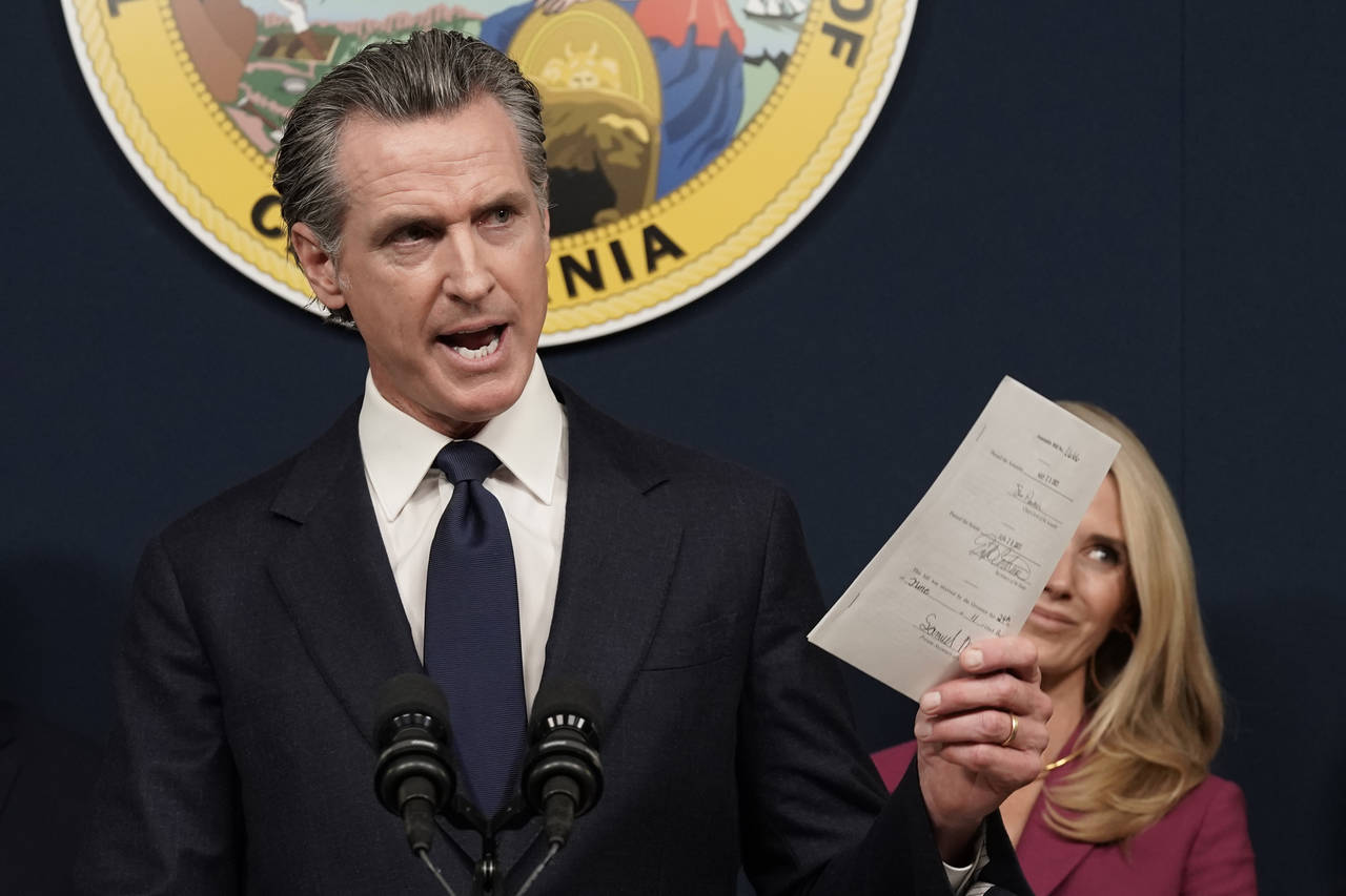 FILE - California Gov. Gavin Newsom displays a bill he signed that shields abortion providers and v...