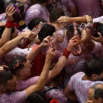 
              Revelers celebrate during the launch of the 'Chupinazo' rocket, to mark the official opening of the 2022 San Fermin fiestas in Pamplona, Spain, Wednesday, July 6, 2022. The blast of a traditional firework opened Wednesday nine days of uninterrupted partying in Pamplona's famed running-of-the-bulls festival which was suspended for the past two years because of the coronavirus pandemic. (AP Photo/Alvaro Barrientos)
            