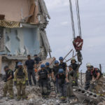 
              Rescue workers sift through rubble at the scene in the after math of a Russian rocket that hit an apartment residential block, in Chasiv Yar, Donetsk region, eastern Ukraine, Sunday, July 10, 2022. At least 15 people were killed and more than 20 people may still be trapped in the rubble, officials said Sunday. (AP Photo/Nariman El-Mofty)
            
