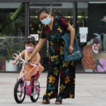 
              A woman helps a child with her bike on the street, Wednesday, July 6, 2022, in Beijing. (AP Photo/Ng Han Guan)
            