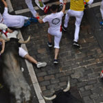 
              Runners fall as people run in the street with fighting bulls during the running of the bulls at the San Fermin Festival in Pamplona, northern Spain, Saturday, July 9, 2022. Revellers from around the world flock to Pamplona every year for nine days of uninterrupted partying in Pamplona's famed running of the bulls festival which was suspended for the past two years because of the coronavirus pandemic. (AP Photo/Alvaro Barrientos)
            