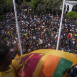 
              Sri Lankan protesters wave Sri Lankan flag after entering the compound of prime minister Ranil Wickremesinghe 's office, demanding he resign after president Gotabaya Rajapaksa fled the country amid economic crisis in Colombo, Sri Lanka, Wednesday, July 13, 2022. (AP Photo/Rafiq Maqbool)
            