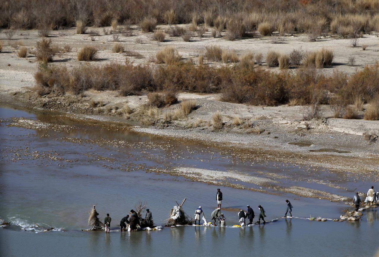 FILE - Afghans try to repair a dam on a river as seen from the British forces forward operating bas...