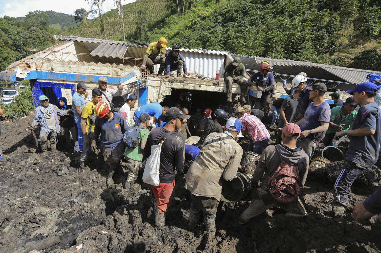 Residents and rescue workers look for survivors at a rural school buried by a landslide caused by h...
