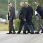 
              Volodymyr Zhukovskyy, left, of West Springfield, Mass., charged with negligent homicide in the deaths of seven motorcycle club members in a 2019 crash, is accompanied by defense attorney Steve Mirkin, second from left, and escorted by court security while visiting the site of the crash on a two-lane highway, in Randolph, N.H., Monday, July 25, 2022. Zhukovskyy has pleaded not guilty to multiple counts of negligent homicide, manslaughter, reckless conduct and driving under the influence in the June 21, 2019, crash. Members of the jury visited the site for a viewing Monday. (AP Photo/Steven Senne, Pool)
            