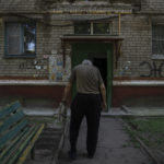 
              Seventy-year-old pensioner Valerii Ilchenko, who lives alone and is refusing to evacuate, walks to his apartment, after filling out his daily crossword, in Kramatorsk, eastern Ukraine, Wednesday, July 6, 2022. Now a widower, Ilchenko says he still has no intention of leaving. "I don't have anywhere to go and don't want to either. What would I do there? Here at least I can sit on the bench, I can watch TV," he says in an interview in his single-room apartment. (AP Photo/Nariman El-Mofty)
            