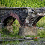 
              The remains of a bridge, destroyed by last year's flood, stands at the small Ahr river in the village of Laach in the Ahrtal valley, Germany, Tuesday, July 6, 2022. Flooding caused by heavy rain hit the region on July 14, 2021, causing the death of about 130 people. (AP Photo/Michael Probst)
            