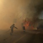 
              A firefighter tries to extinguish the flames next to motorcycles during a wildfire near Megara town, west of Athens, Greece, Wednesday, July 20, 2022. The new fire broke out in the hills outside the town of Megara, 40 kilometers (25 miles) to the west, prompting a new, but more limited, round of evacuations. (AP Photo/Petros Giannakouris)
            