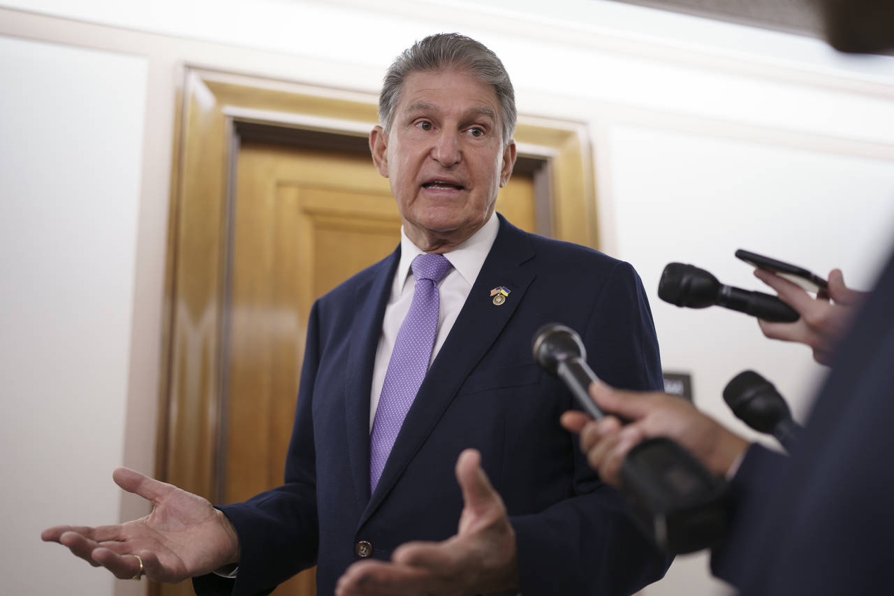 FILE - Sen. Joe Manchin, D-W.Va., is met by reporters outside the hearing room where he chairs the ...