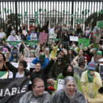 
              Abortion-rights demonstrators shout slogans after tying green flags to the fence of the White House during a protest to pressure the Biden administration to act and protect abortion rights, in Washington, Saturday, July 9, 2022. (AP Photo/Jose Luis Magana)
            