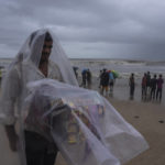 
              A street hawker covers himself with plastic sheet in rain as he waits for customer to sell cigarettes and chewable tobacco at Juhu beach in Mumbai, India, Thursday, June 30, 2022. India banned some single-use or disposable plastic products Friday as a part of a longer federal plan to phase out the ubiquitous material in the nation of nearly 1.4 billion people. (AP Photo/Rafiq Maqbool)
            