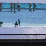 
              People swim in the elevated pool, called Sky Pool, in London, Monday, July 18, 2022. Britain's first-ever extreme heat warning is in effect for large parts of England as hot, dry weather that has scorched mainland Europe for the past week moves north, disrupting travel, health care and schools. (AP Photo/Alberto Pezzali)
            