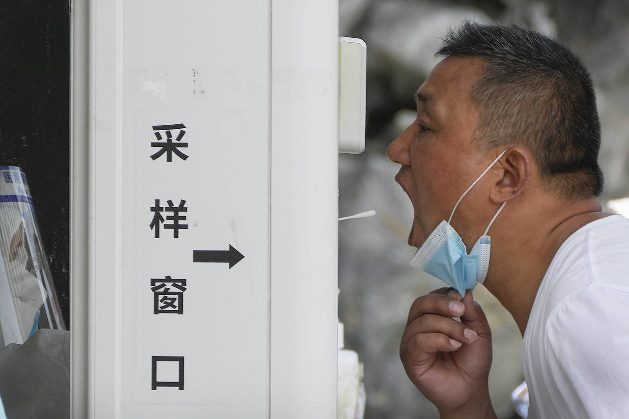 A man gets a throat swab at a testing site as people are required for a negative COVID test in the ...