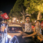 
              Tunisians celebrate the exit polls indicating a vote in favor of the new Constitution, in Tunis, late Monday, July 25, 2022. Hundreds of supporters of Tunisian President Kais Saied took to the streets to celebrate after the end of voting on a controversial new constitution that critics say could reverse hard-won democratic gains and entrench a presidential power grab. (AP Photo/Riadh Dridi)
            