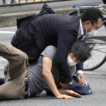 
              Tetsuya Yamagami, bottom, is detained near the site of gunshots in Nara Prefecture, western Japan, Friday, July 8, 2022. Former Japanese Prime Minister Shinzo Abe, a divisive arch-conservative and one of his nation's most powerful and influential figures, has died after being shot by Yamagami during a campaign speech Friday in western Japan, hospital officials said.(Katsuhiko Hirano/The Yomiuri Shimbun via AP)
            