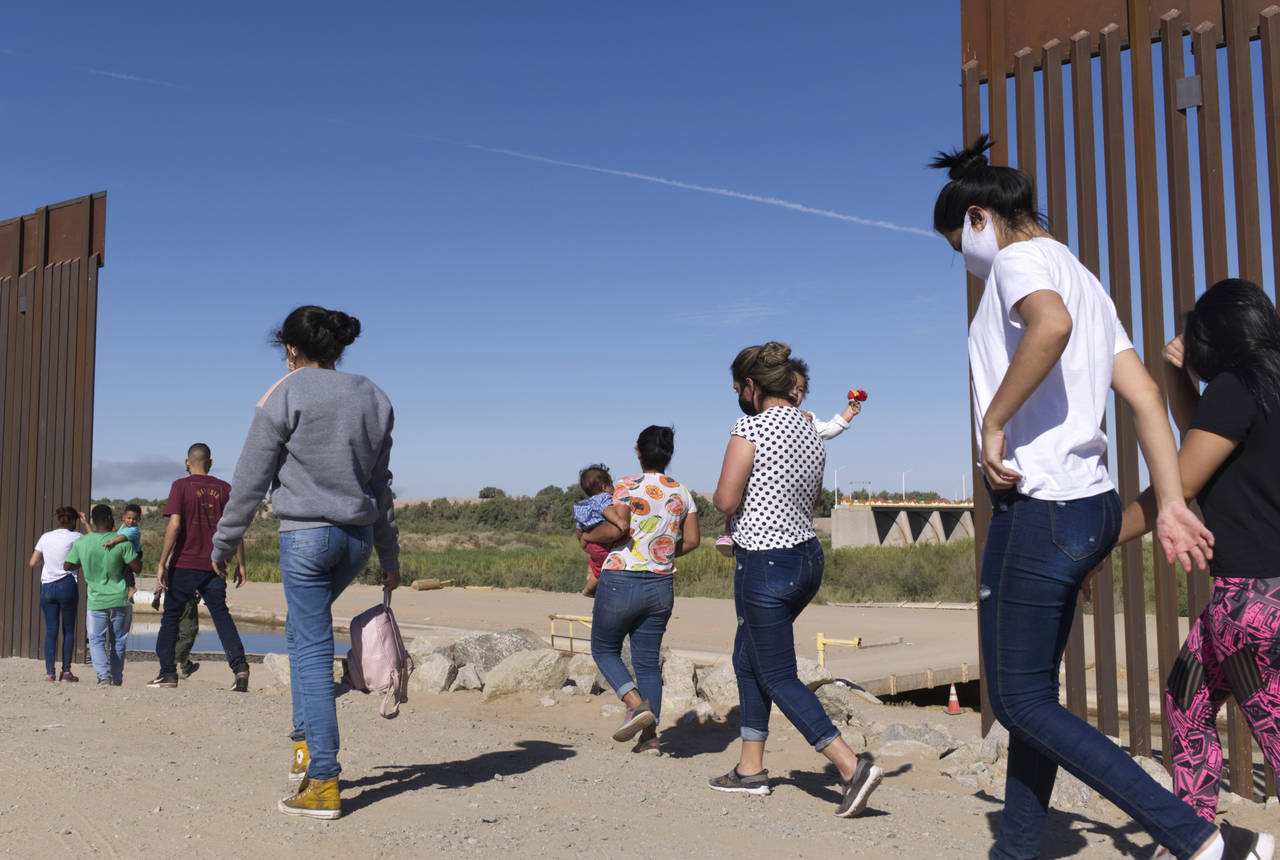 FILE - A group of Brazilian migrants make their way around a gap in the U.S.-Mexico border in Yuma,...