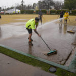 
              Workers clear mud from a bowling green at Camden on the outskirts of Sydney, Australia, Monday, July 4, 2022. More than 30,000 residents of Sydney and its surrounds have been told to evacuate or prepare to abandon their homes on Monday as Australia's largest city braces for what could be its worst flooding in 18 months. (AP Photo/Mark Baker)
            