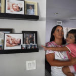
              Laura Guerra and her daughter Emilia, 2, look at her father's pictures at their home in Riverside, Calif., on Monday, July 11, 2022. For now, Laura is focused on making sure her daughter, Emilia, remembers her father.  Rigo Guerra passed away on Dec. 24, 2020, due to complications following a monthlong battle with COVID-19.  California has approved trust funds for some children from low-income families who lost a parent or caregiver to COVID-19. The Legislature set aside $100 million in the state budget to put into trust funds.   (AP Photo/Damian Dovarganes)
            