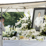 
              A person offers flowers and prayers for former Prime Minister Shinzo Abe, at Zojoji temple prior to his funeral wake Monday, July 11, 2022, in Tokyo. Abe was assassinated Friday while campaigning in Nara, western Japan. (AP Photo/Eugene Hoshiko)
            