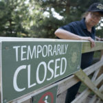
              An employee stands by a gate at the Yorkshire Wildlife Park in Doncaster, which is temporarily closed due to the hot weather as record temperatures hit the UK, Monday July 18, 2022. Britain’s first-ever extreme heat warning is in effect for large parts of England as hot, dry weather that has scorched mainland Europe for the past week moves north, disrupting travel, health care and schools. (Danny Lawson/PA via AP)
            