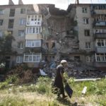 
              FILE - A woman walks past a building damaged by shelling in Slovyansk, eastern Ukraine, Thursday, July 10, 2014. (AP Photo/Evgeniy Maloletka, File)
            