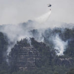 
              A helicopter of the German Federal Police battles wildfires in the Saxon Switzerland National Park near Schmilka, Germany, Wednesday, July, 27, 2022. (Robert Michael/dpa via AP)
            
